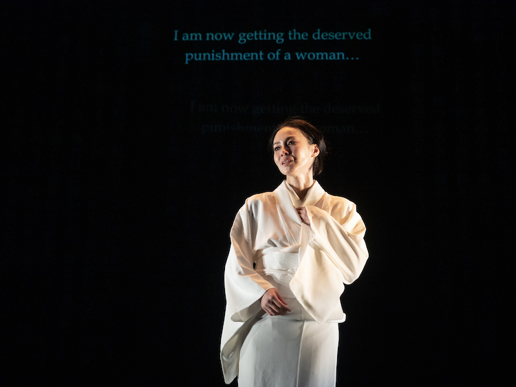 Miki Nakatani in a pure white kimono with hair upright speaks tearfully to us behind her are the projected words